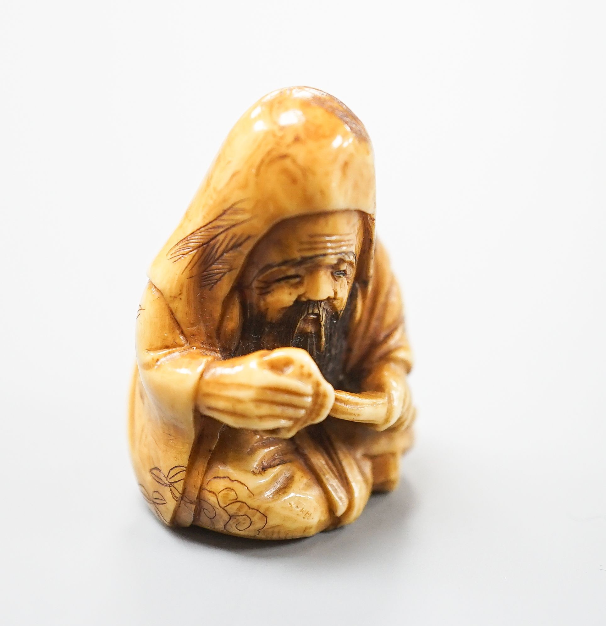 A Japanese ivory netsuke of Fukurokuju seated, holding a sceptre, early 20th century, 3.8cm